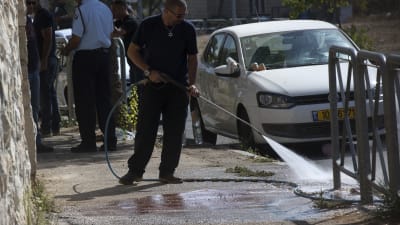 En kommunalarbetare tvättar gatan i Jerusalem där den palestinska tonåringen sköts ihjäl under lördagsmorgonen.
