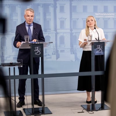 Ministrarna Ohisalo och Haavisto i Statsrådets presskonferens, bakom talarstolar med statslejonet som dekoration