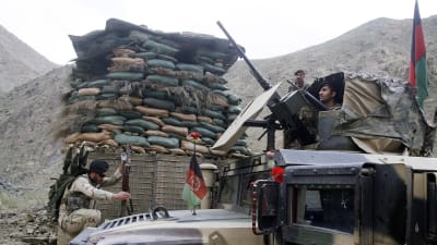 Tungt beväpnade afghanska soldater vid en bepansrad bil i norra Afghanistan.