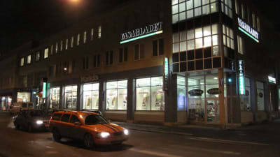 Hus med Vasabladets logotyp. Bilden är tagen efter mörkrets infall, och i förgundens syns en orange Volvo V70.