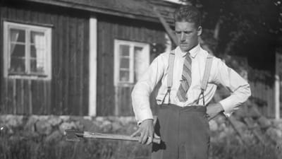 En man lyfter en yxa. Bilden är tagen 1930 i Bromarf.