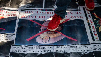 En röd sko trampar på en affisch. 