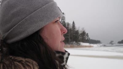 Kvinna i profil tittar ut över vintrigt hav