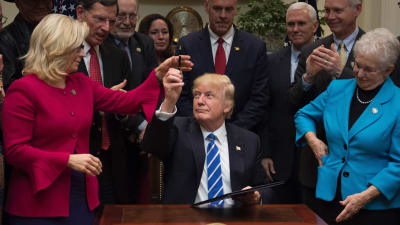 Donald Trump, omgiven av republikanska politiker, undertecknar resolutioner i Vita huset 27.3.2017