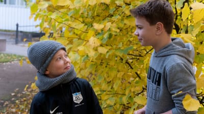 Två pojkar står mittemot varandra utomhus. 