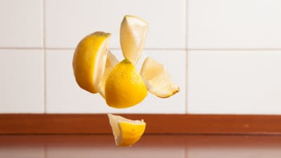 Citronklyftor faller mot ett bord.