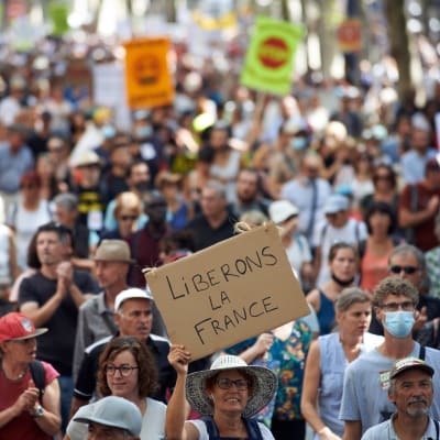 Människor demonstrerar mot coronadirektiv i Frankrike. En person håller upp en skylt med texten "Frihet åt Frankrike".