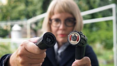 Kvinna med glasögon håller upp uppsågat cykellås mot kameran. Det är ett kombinationslås.