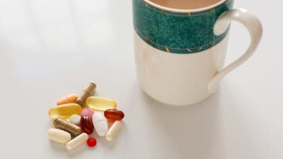 Vitaminer ligger på ett bord bredvid en kaffekopp.