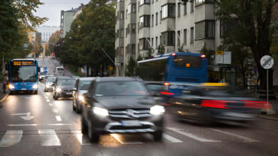 Bilar åker på en väg inne i Helsingfors centrum.