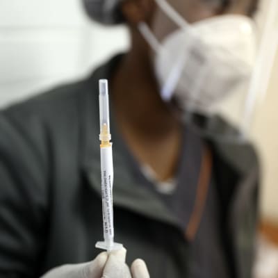 En person håller upp en spruta med ett coronavirusvaccin i testningsskedet.