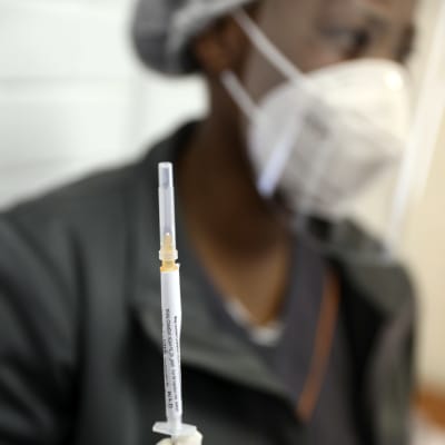 En person håller upp en spruta med ett coronavirusvaccin i testningsskedet.