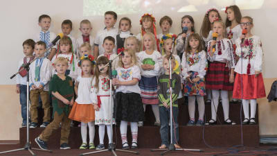 En grupp med barn står på en scen och sjunger.