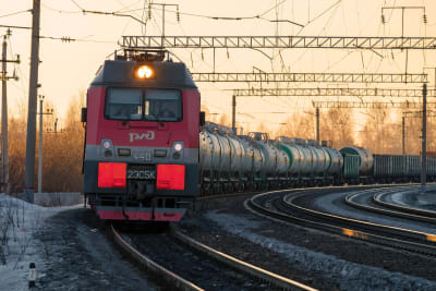 Ett rött elektriskt lok drar ett långt godståg.