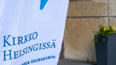 Lähikuva Kirkko Helsingissä -tekstistä Lauttasaaren seurakunnan sisäänkäynnin edustalla olevassa lipussa.