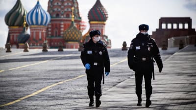 Två poliser patrullerar på ett näst intill tomt Röda torget i Moskva.