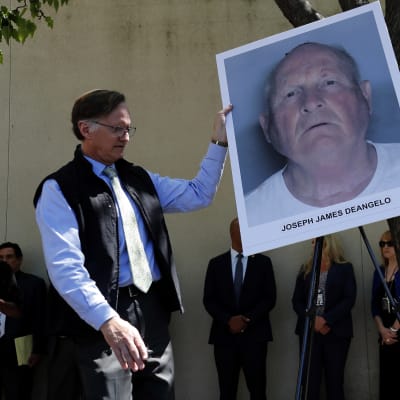 En polis håller upp en bild av Golden State-mördaren Joseph James DeAngelo.