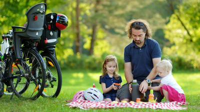 pappa på en picnic-filt med två barn