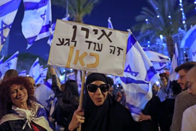 En kvinna i solglasögon och svart chador bär ett plakat som varnar för att Israel kan komma att bli som Iran.