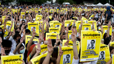 Demonstrerande studenter i Bangkok håller upp bilder på demokratiaktivister som har försvunnit spårlöst efter att ha flytt undan militären till grannlandet Kambodja.