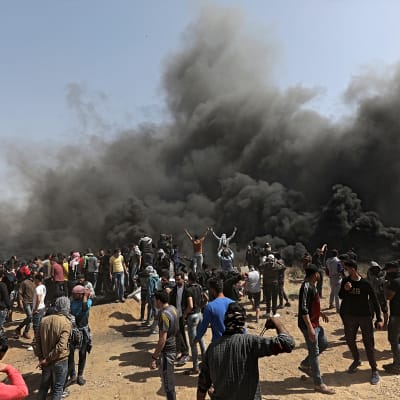 Palestinska demonstranter står bakom rökridåer nära gränsen mellan Israel och Gaza. 
