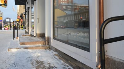 Bild av ett fönster vid gatan som lyses upp av solstrålar. Snö på marken. 