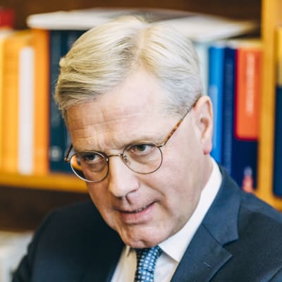 Norbert Röttgen i kostym och glasögon sitter framför en bokhylla.