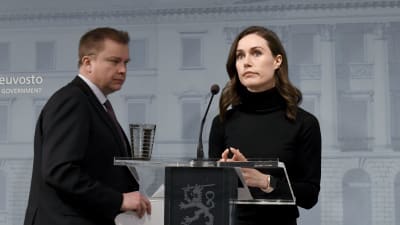 Antti Kaikkonen och Sanna Marin står bakom ett podium klädda i svart.