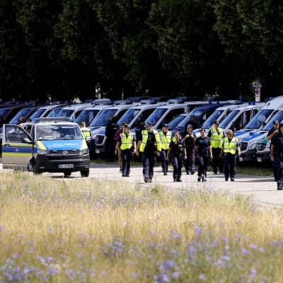 Lång rad med poliser i gula västar framför polisbilar i Tyskland. 
