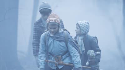 Tre barn promenerar genom en tjock dimma.