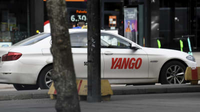 En vit taxibil med företaget Yangos logo.