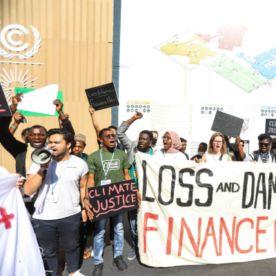 Unga demonstranter håller upp plakat och banderoller om klimaträttvisa och om att väst måste betala för förlust och skada.