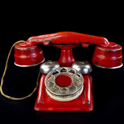 En röd telefon med roterande nummerbricka.