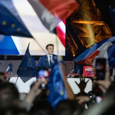 Ranskan presidentti Emmanuel Macron puhuu äänestäjille vaalituloksen ratkettua. Taustalla näkyy Eiffelin torni. Kannattajat liehuttavat Ranskan ja EU:n lippuja. 