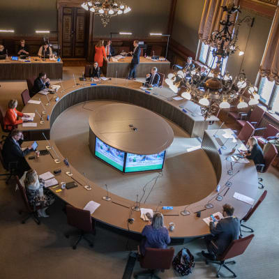 Bild från takkanten: Regeringen samlas runt stort mötesbord i Ständerhusets sal