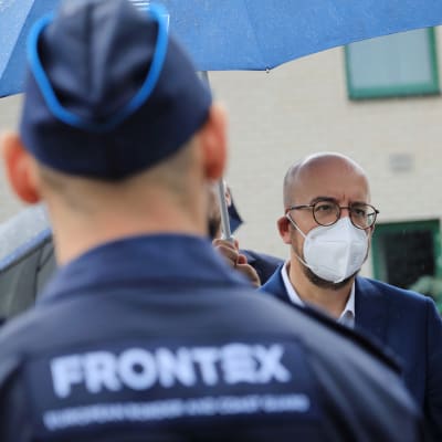 Bild på baksidan av en man i Frontex-uniform. Bakom honom står Europeiska rådets ordförande Charles Michel.