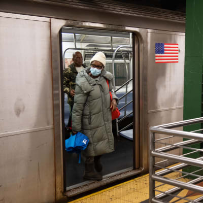 Kvinna med ansiktsskydd stiger av metron i New York