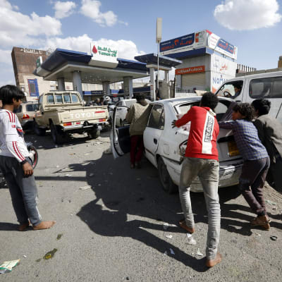 Ihmiset työntävät autoa huoltoasemalle Jemenissä.