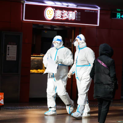 Suojapuvuin varustautuneita terveydenhuollon vapaaehtoistyöntekijöitä rautatieasemalla Pekingissä. 