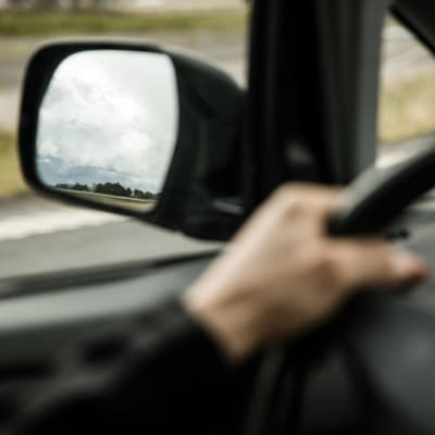 Backspegel och hand på bilratt