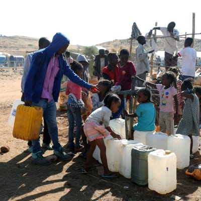 Lapset keräävät vettä kanistereihin Um Rakuban pakolaisleirillä Sudanissa.