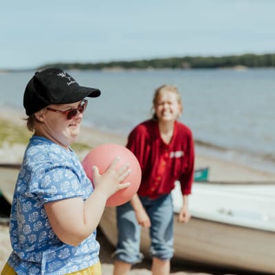 två personer kastar boll på stranden