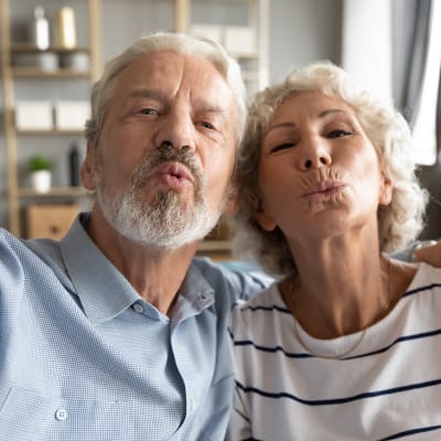 Äldre man och kvinna gör pussmunnar mot kameran