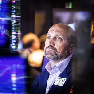 En man sitter och tittar på dataskärmar inne i Wall Street-byggnaden.