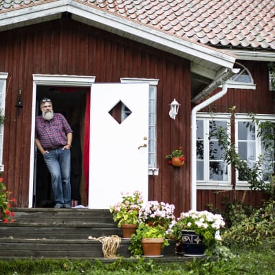 Patrick Sellman står vid dörren till sitt röda hus.