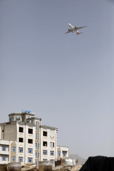 Bild på ett vitt hus och ett flygplan i luften ovanför.