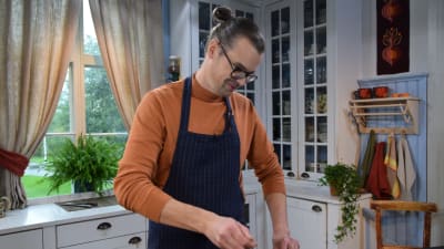 Mies keittiössä valmistelee ruokaa leiden äärellä