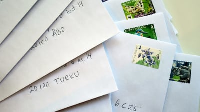 Vita kuvert med adresser och frimärken på.