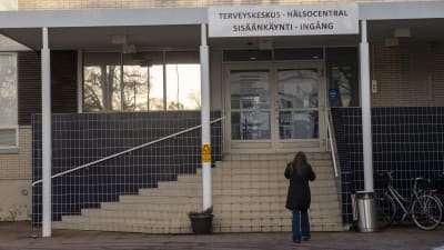 En person går mot ingången till en hälsocentral.