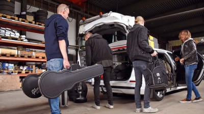Bandmedlemmar packar en bil ful med instrument och kappsäckar.